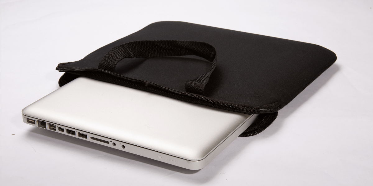 A silver laptop partially slides out of a sleek black carrying case resting on a plain white surface. The scene is minimalistic and functional, evoking a sense of simplicity and readiness.